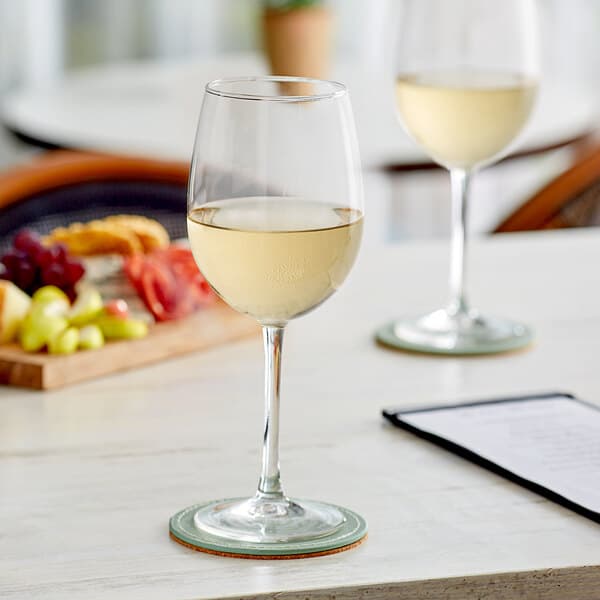 Two Acopa Select Flora wine glasses of white wine on a table
