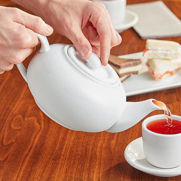 a person pouring tea into a cup