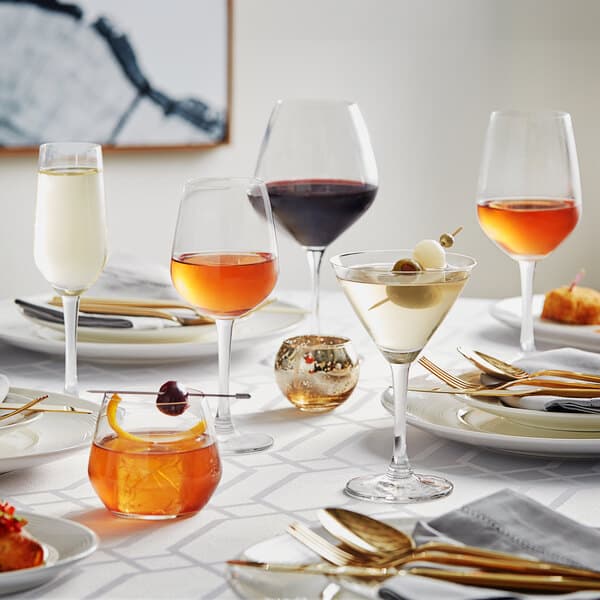 Acopa Radiance wine glasses on a table with glasses of wine and food.