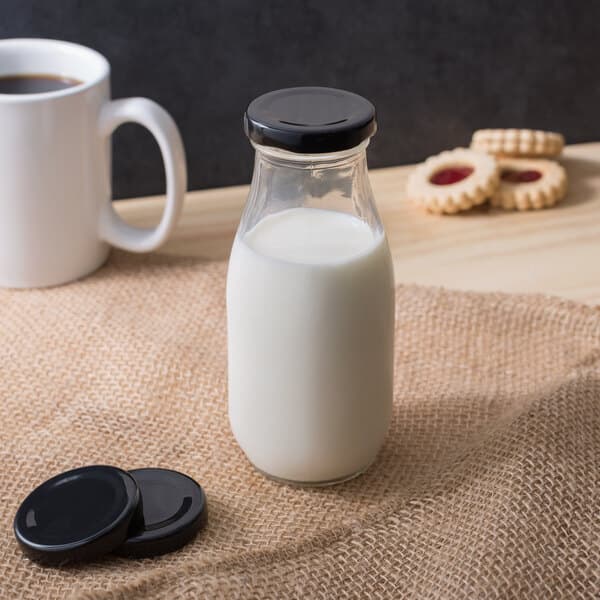 A bottle of milk with a black Acopa round lid on a table.