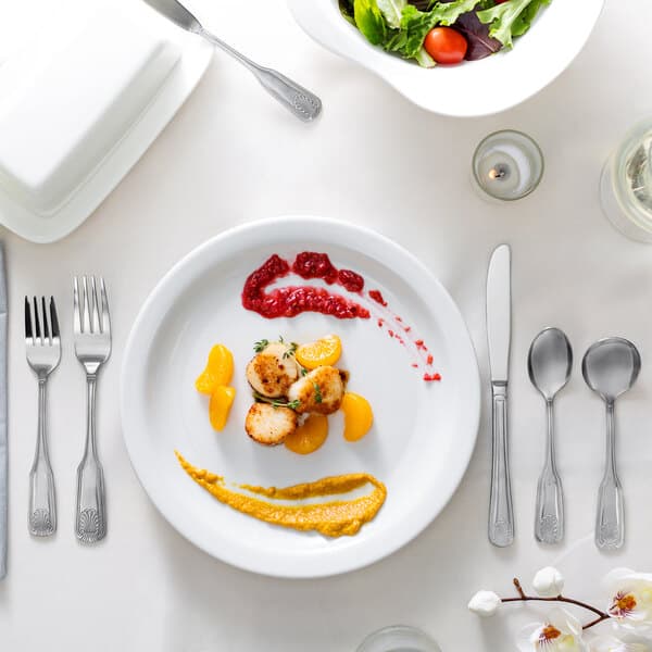 A silver Acopa knife on a white plate with food.