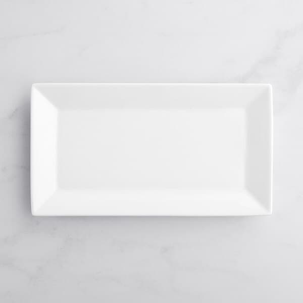 An Acopa bright white rectangular porcelain platter on a marble surface.