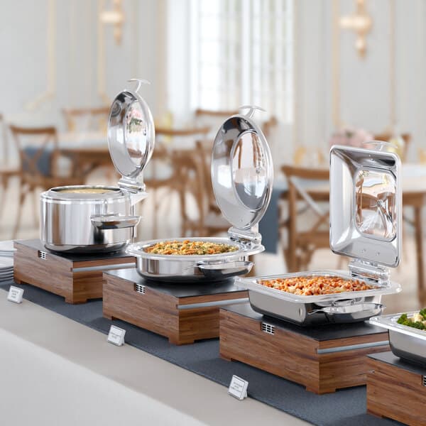 An Acopa Voyage stainless steel chafer with a glass lid on a buffet table.