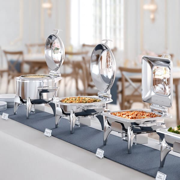 An Acopa Voyage stainless steel soup chafer on a buffet table with food.