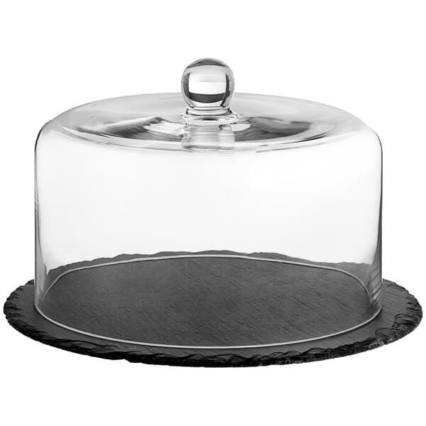 A black slate tray with a glass dome on a table in a bakery display.
