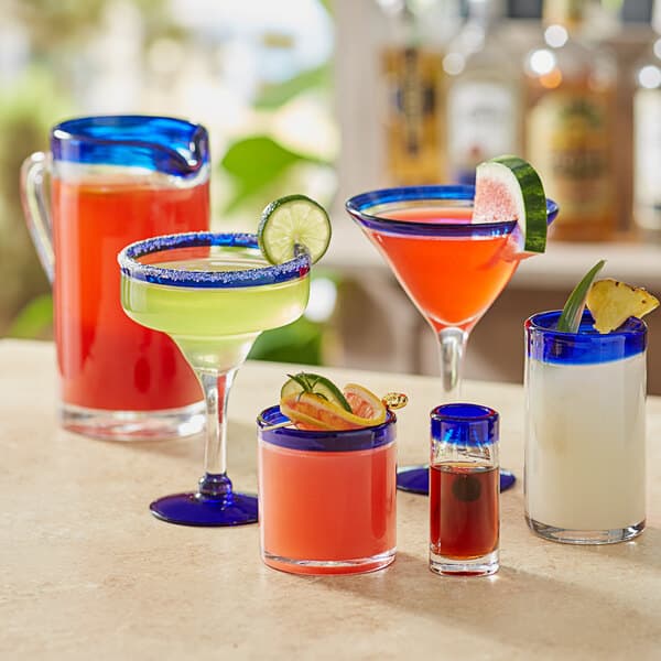 A table with Acopa Tropic rocks glasses filled with different colored drinks.