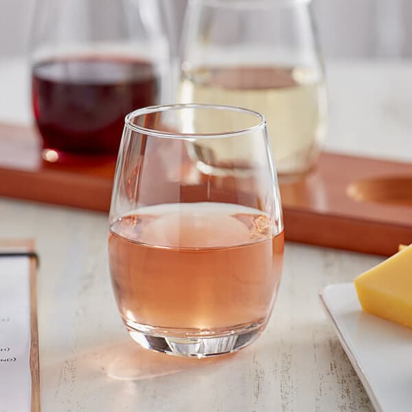 A tray of Acopa stemless wine glasses on a table with a glass of wine
