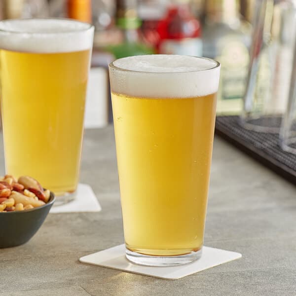 Two Acopa mixing glasses of beer on a bar counter.