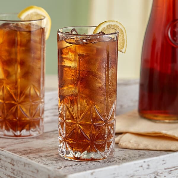 A close-up of an Acopa Gardenia highball glass filled with iced tea and a lemon slice.