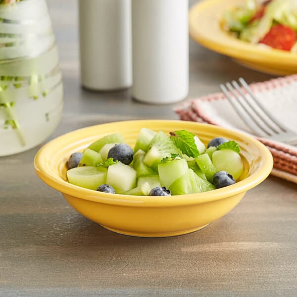 An Acopa Capri citrus yellow stoneware bowl filled with fruit and blueberries.