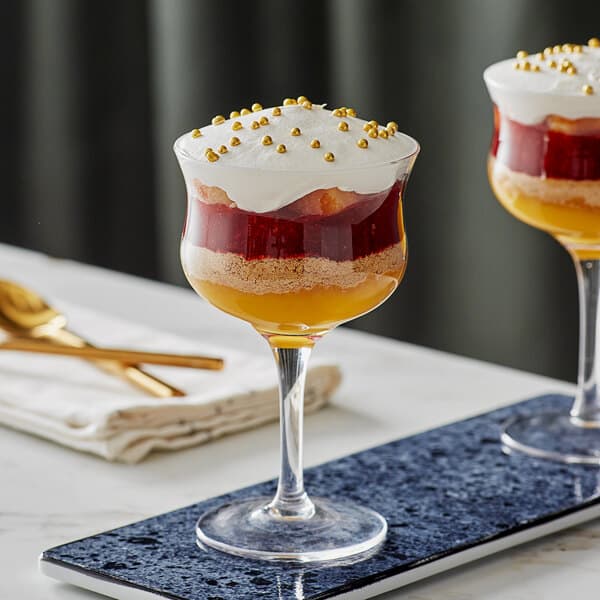 Two Acopa Deco rose / cocktail glasses filled with desserts on a tray.