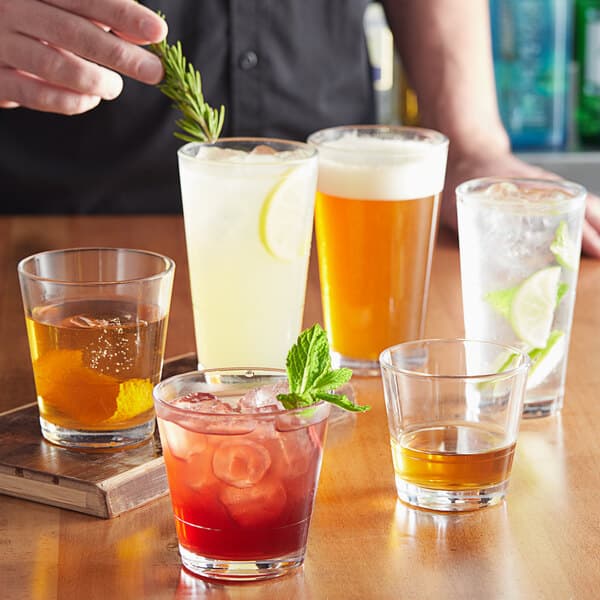 A bartender pouring drinks into Acopa Select stackable beverage glasses on a table in a bar.