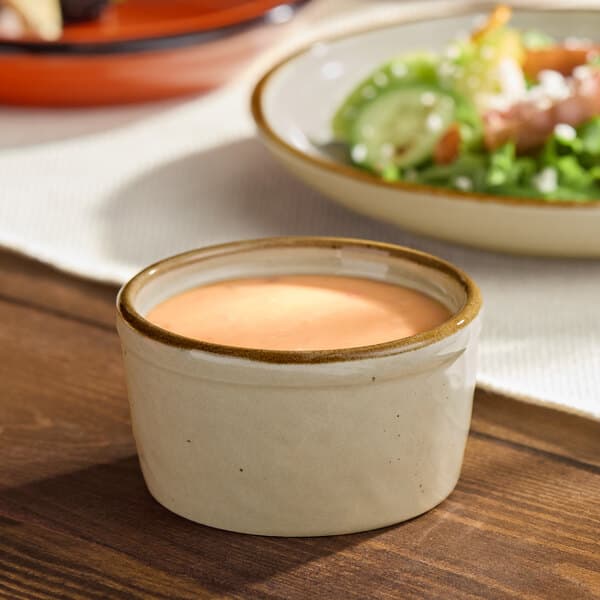 A small granite gray stoneware ramekin filled with a creamy dressing or sauce.