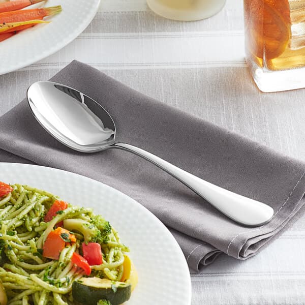 An Acopa Vernon stainless steel serving spoon on a plate of food.