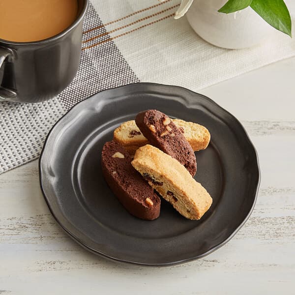 An Acopa Condesa porcelain plate with chocolate cookies and a mug of coffee on a table.