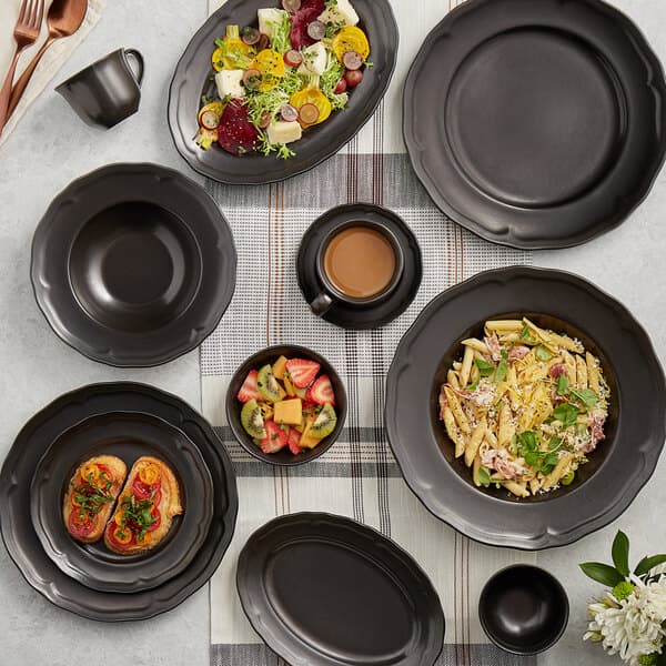 A table set with Acopa Condesa matte gray porcelain plates, bowls, and black coffee cups.