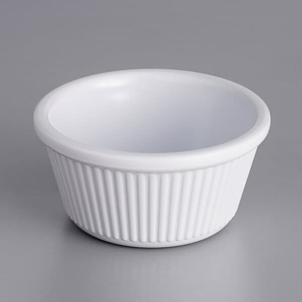 A white fluted Acopa ramekin on a gray surface.