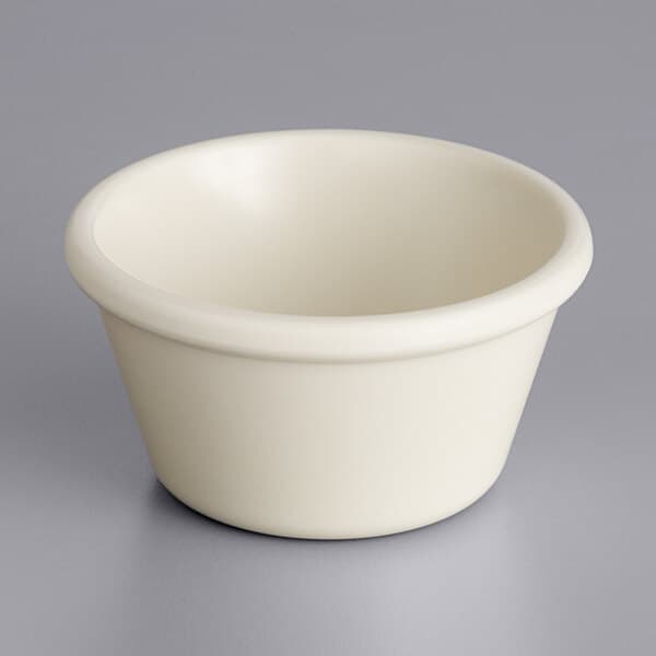 An Acopa bone white melamine ramekin on a gray surface.