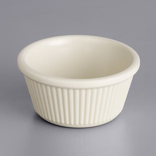 An Acopa Bone White fluted ramekin on a gray surface.