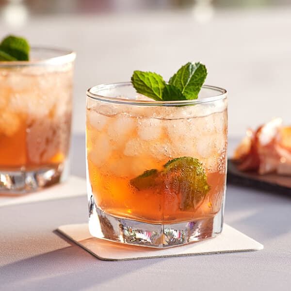 Two Acopa Cube rocks glasses with ice tea and mint on a table.