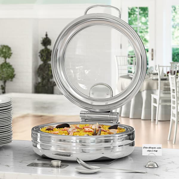 A buffet with a stainless steel Acopa Manchester chafer on a table outdoors.