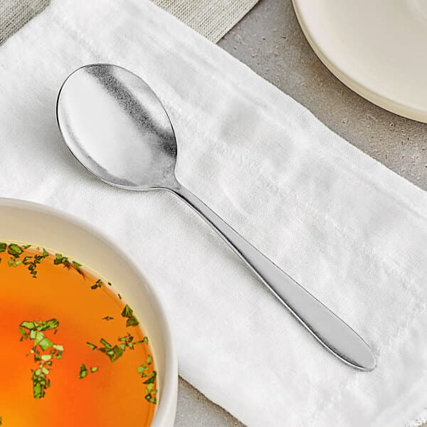 An Acopa Pangea bouillon spoon next to a bowl of broth.