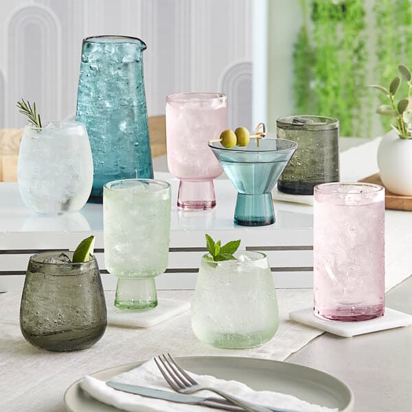 A table with Acopa mauve, blue, and green martini glasses and utensils.