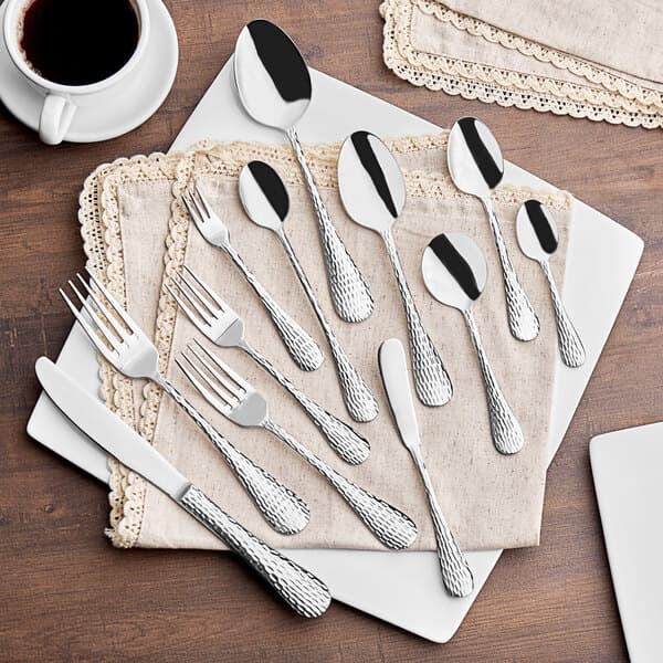 An Acopa stainless steel oval bowl dinner/dessert spoon on a table with other silverware.
