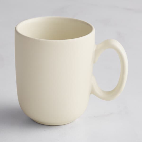 A close-up of an Acopa Pangea fog white matte porcelain cup with a handle.