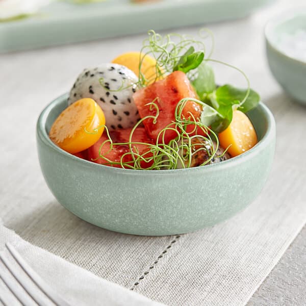 A bowl of fruit in an Acopa Harbor Blue ramekin on a table.