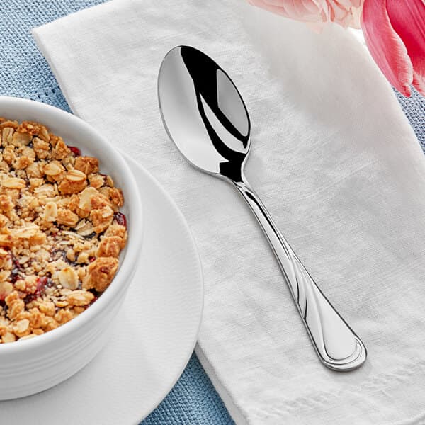 A bowl of oatmeal with an Acopa stainless steel teaspoon on a table.