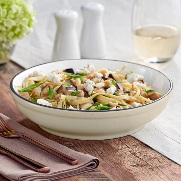 An Acopa Embers stoneware pasta bowl filled with pasta, vegetables, and cheese on a table.