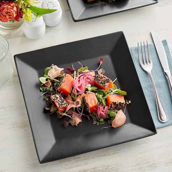 A salmon salad and vegetables on a black Acopa stoneware plate.