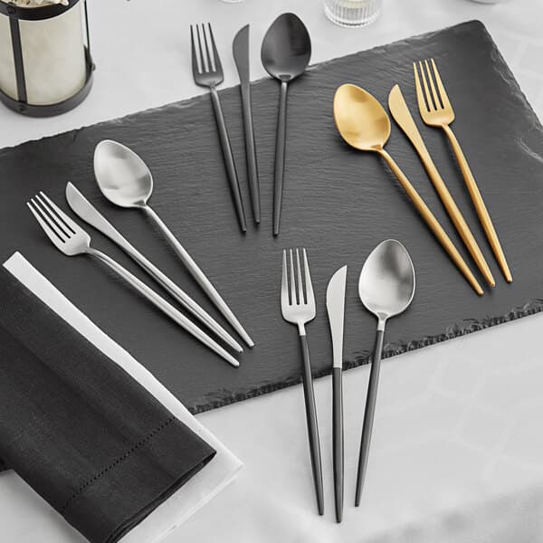 Acopa Odin Black stainless steel flatware on a black surface.