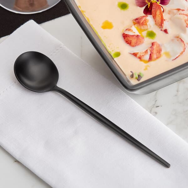 An Acopa Odin stainless steel bouillon spoon in a bowl of food.