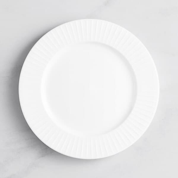 An Acopa Cordelia porcelain plate with a wide, rippled edge and a circular pattern on a white surface.