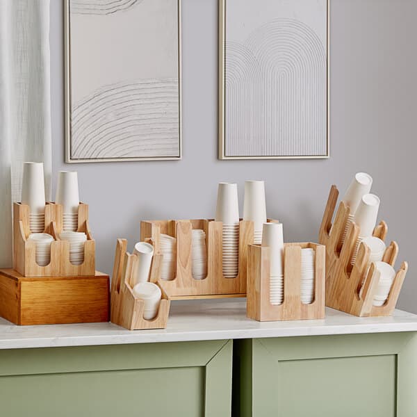 An Acopa wood cup and lid organizer holding paper cups on a counter.