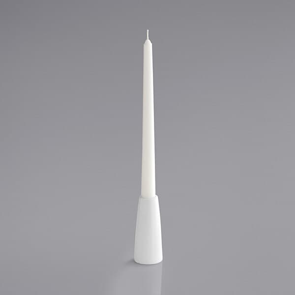 A white pillar candle in a white Acopa taper holder.