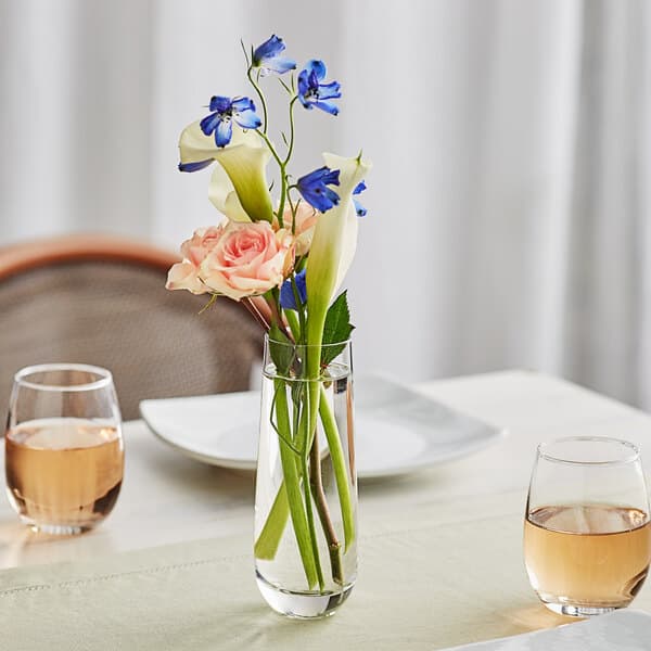 An Acopa Bala glass bud vase with flowers on a table.