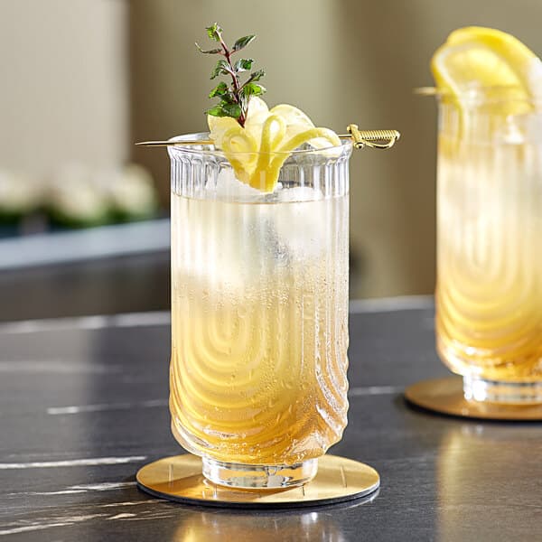 Two Acopa Zelda highball glasses with a lemon drink and rosemary on a table.