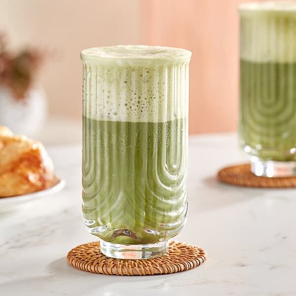 An Acopa Zelda highball glass with green liquid on a table in a juice bar.