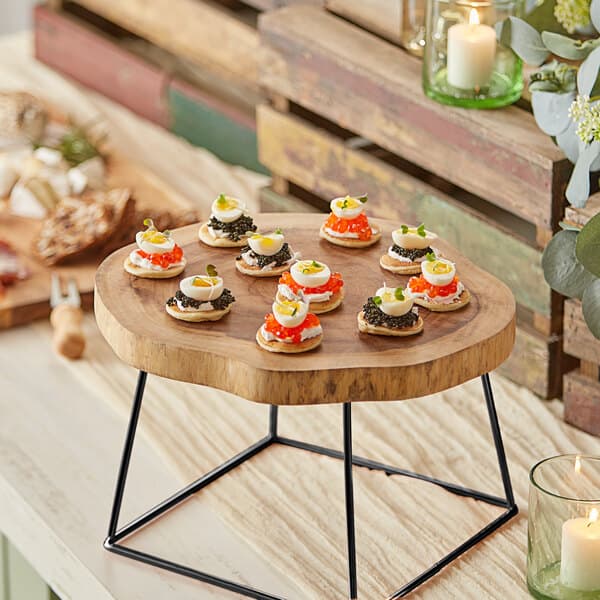 An Acopa round wooden serving board with food on it.