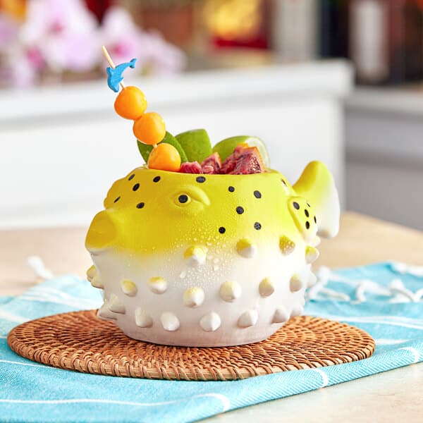 A yellow and white ceramic fish shaped mug on a table.
