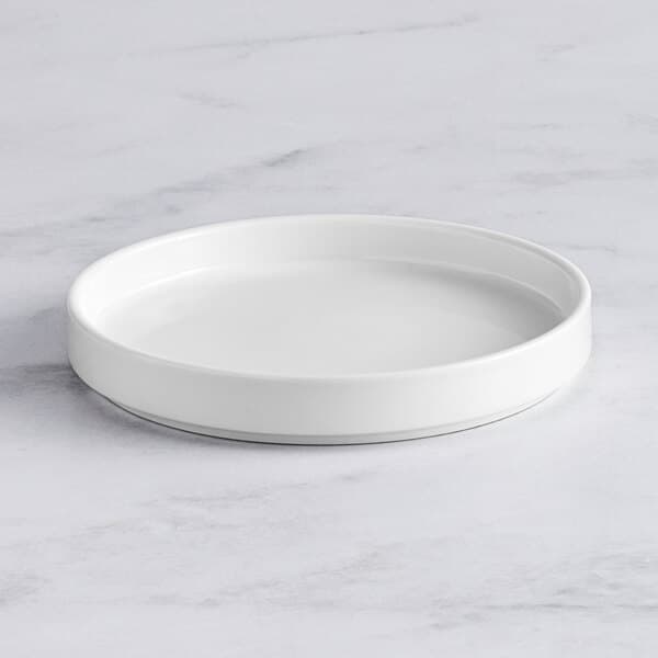 An Acopa Lore bright white porcelain plate on a marble surface.