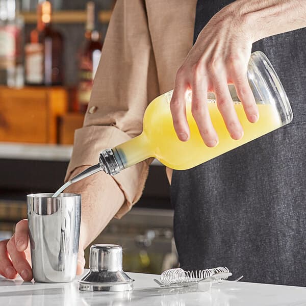 A person pouring a drink into a Nordic glass bottle.