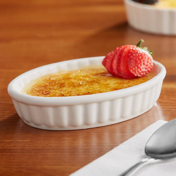 An Acopa ivory porcelain creme brulee dish with a strawberry on top.