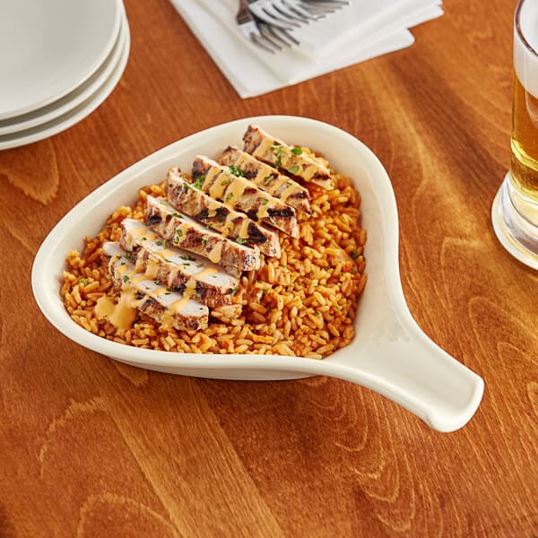 An Acopa ivory stoneware bowl filled with rice and meat on a table.