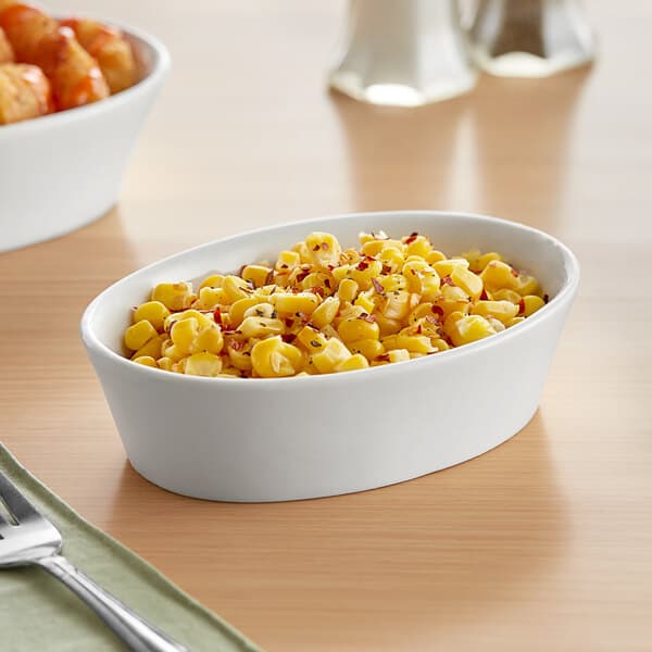 A white Acopa porcelain bowl filled with corn on a table.