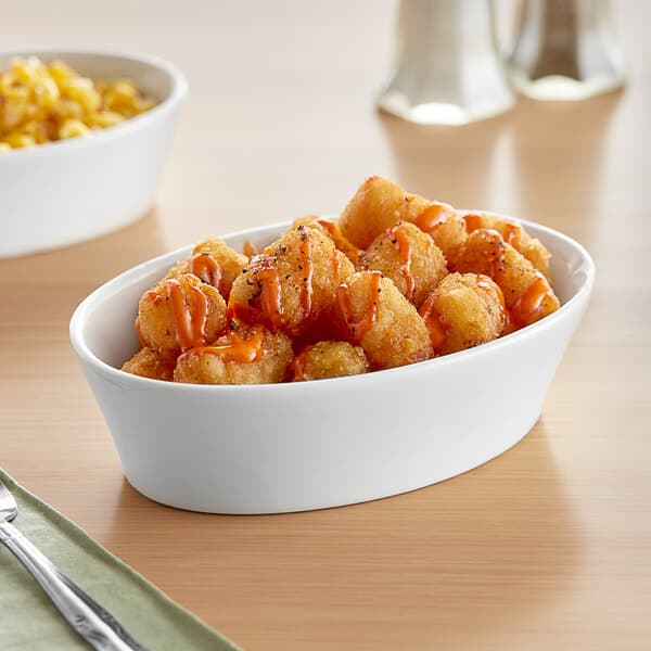 A white Acopa oval baker dish filled with food with sauce.