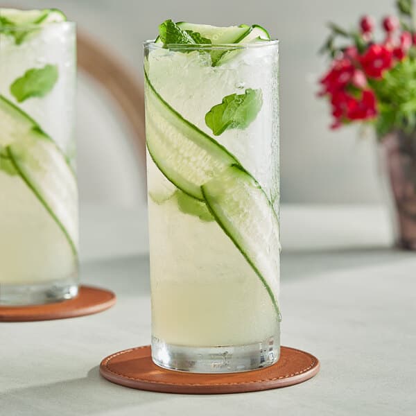 Two Acopa Collins glasses of cucumber water with mint leaves.